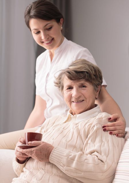 Young female caregiver taking care of older woman